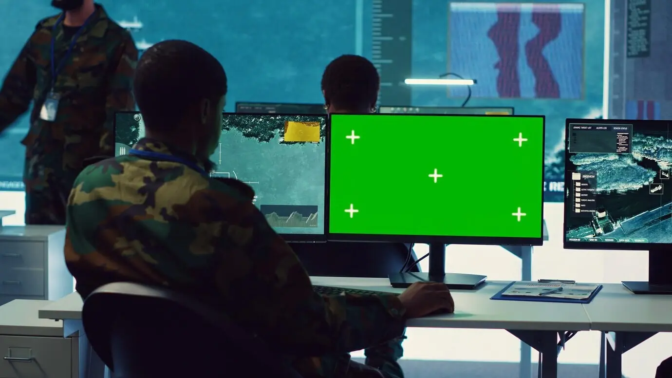 Analista de inteligencia revisa la actividad de barcos junto a una maqueta de pantalla aislada.